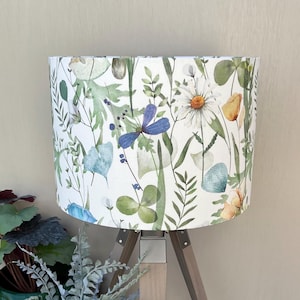White lampshade with blue and yellow flowers on a wooden table lamp.