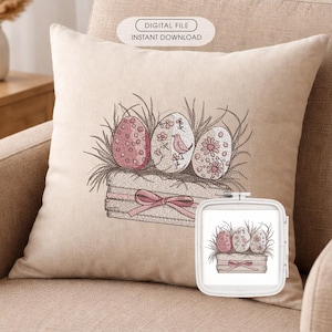 May include: A beige cushion with an embroidered Easter design. The design shows three decorated eggs in a wooden box with a pink bow. The eggs are pink and white, with floral and bird details. The text "DIGITAL FILE INSTANT DOWNLOAD" is at the top.