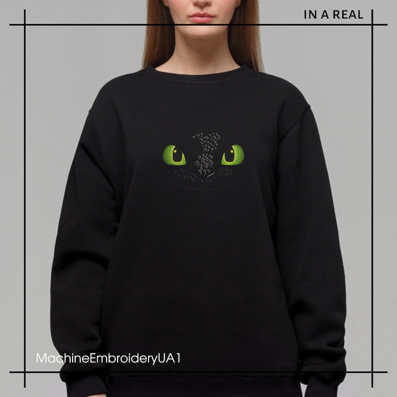Pu&ograve; includere: Felpa nera con un designo ricamato di occhio di drago verde. Il design &egrave; centrato sulla parte anteriore della felpa.