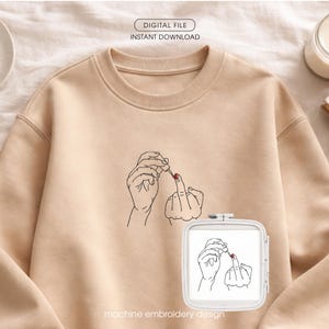 Puede incluir: Sudadera beige con un dibujo lineal negro de manos aplicando esmalte de uñas rojo a un dedo corazón. El texto "DIGITAL FILE INSTANT DOWNLOAD" está en la parte superior y "machine embroidery design" en la inferior.