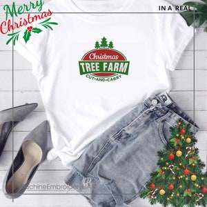 K&ouml;nnte beinhalten: Wei&szlig;es T-Shirt mit einem gr&uuml;n-roten Weihnachtsbaum-Farm-Logo. Das Logo zeigt den Text "Christmas Tree Farm" mit den Worten "Cut and Carry" darunter.