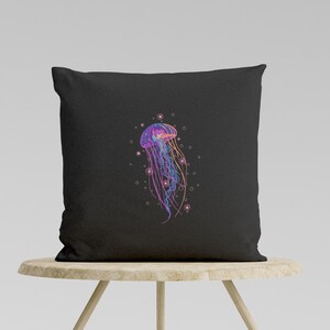 May include: A black pillow with a colorful jellyfish illustration. The jellyfish is pink, purple, and blue with a white outline. The background is black with white dots.