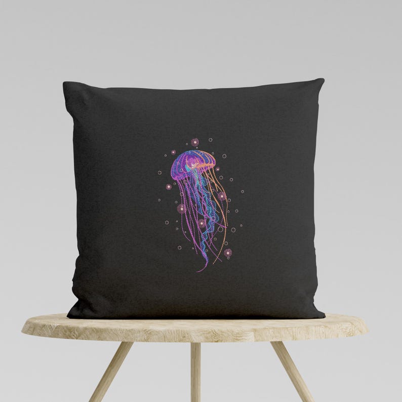 May include: A black pillow with a colorful jellyfish illustration. The jellyfish is pink, purple, and blue with a white outline. The background is black with white dots.