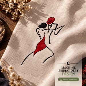 Può includere: Un tessuto beige con un ricamo a macchina raffigurante due figure che ballano. Il disegno utilizza filo nero per i contorni e un cappello e un vestito rossi. Il testo recita MACHINE EMBROIDERY DESIGN e DIGITAL DOWNLOAD con un'icona a mezzaluna.