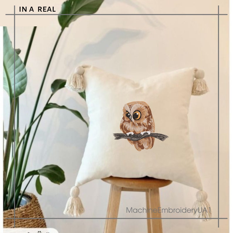 May include: Square cream cushion featuring an embroidered owl on a branch. The cushion has four corner tassels and the text "IN A REAL" at the top left. The text "MachineEmbroideryUA1" is at the bottom right.
