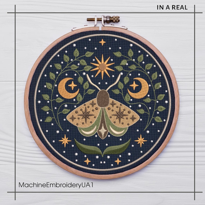 May include: A round embroidery hoop featuring a detailed moth design. The moth is in shades of brown and green, surrounded by crescent moons, stars, and foliage on a dark blue background. The text "IN A REAL" is at the top and "MachineEmbroideryUA1" at the bottom.