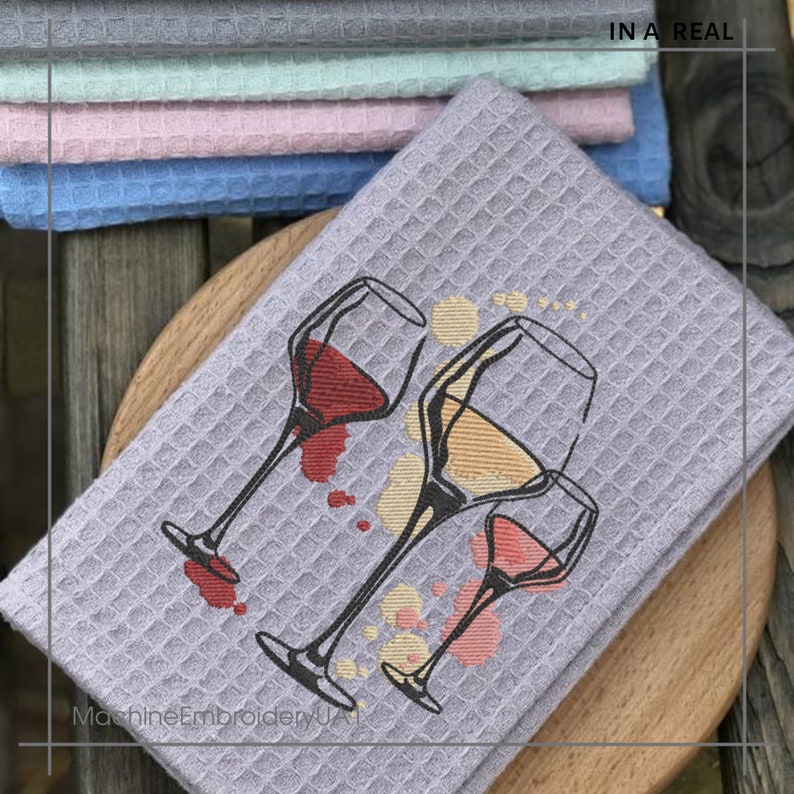 K&ouml;nnte beinhalten: Ein graues K&uuml;chentuch mit Waffelstruktur zeigt ein gesticktes Design mit drei Weingl&auml;sern mit rotem, wei&szlig;em und rosafarbenem Wein. Die Gl&auml;ser sind teilweise gef&uuml;llt und haben Weintropfen, die um sie herum versch&uuml;ttet wurden. Der Text "MachineEmbroideryUA" ist in der linken unteren Ecke sichtbar.
