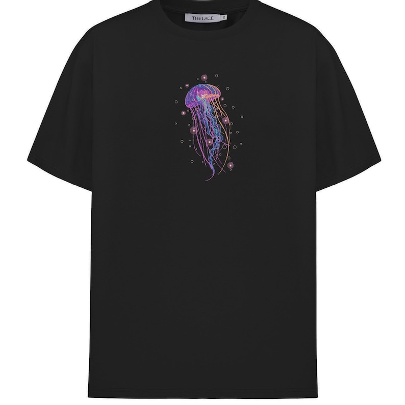 May include: Black t-shirt with a graphic of a purple and pink jellyfish with a white outline. The jellyfish is surrounded by small white circles.