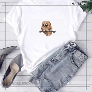 May include: White t-shirt with an embroidered owl design. The owl is brown and tan, with yellow eyes, perched on a branch. The text "IN A REAL" is in the upper right corner. The text "MachineEmbroideryUA" is in the lower left corner.