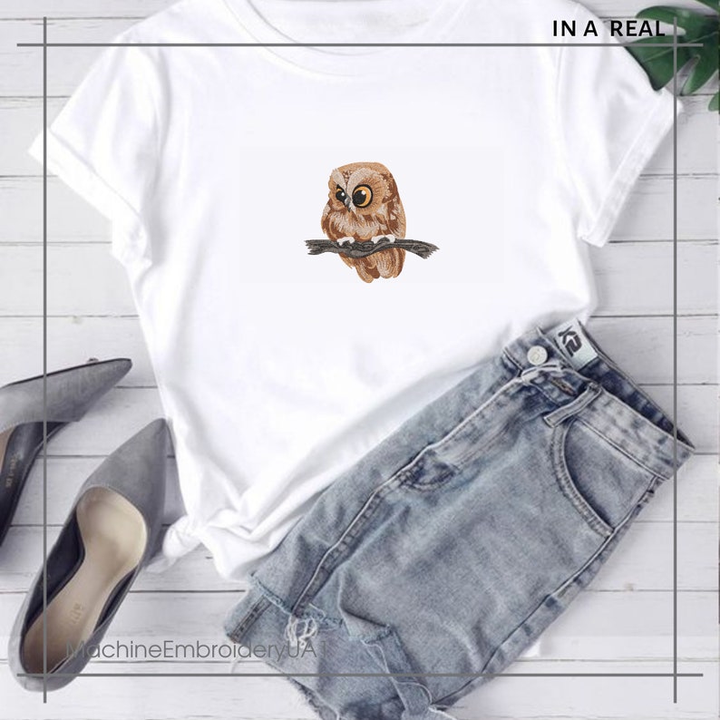 May include: White t-shirt with an embroidered owl design. The owl is brown and tan, with yellow eyes, perched on a branch. The text "IN A REAL" is in the upper right corner. The text "MachineEmbroideryUA" is in the lower left corner.
