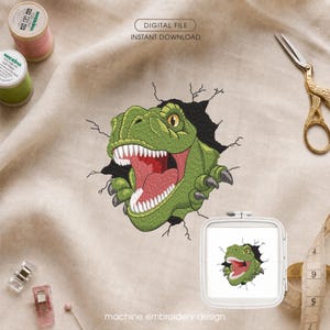 Può includere: Un disegno per ricamo a macchina con una testa di Tyrannosaurus Rex verde che rompe un muro nero. Il disegno include denti bianchi affilati, una bocca rossa e occhi gialli. Il testo recita DIGITAL FILE INSTANT DOWNLOAD e machine embroidery design.