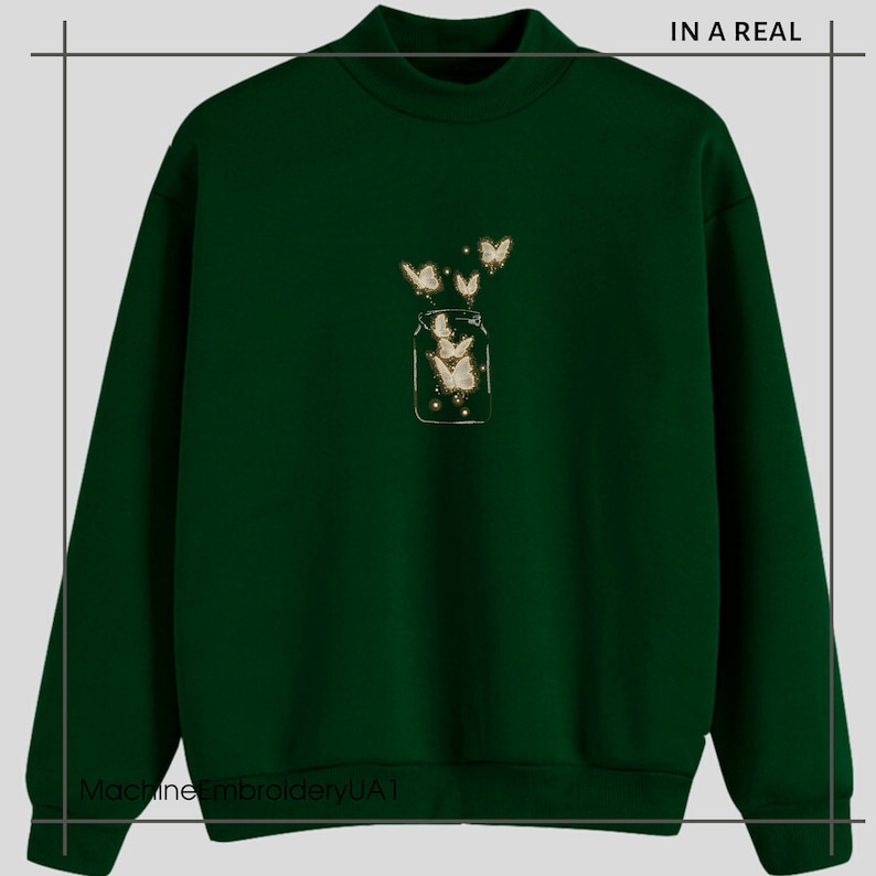 May include: A dark green sweatshirt with a white embroidered design of a jar with butterflies flying out of it. The text "IN A REAL" is in the top right corner of the image.