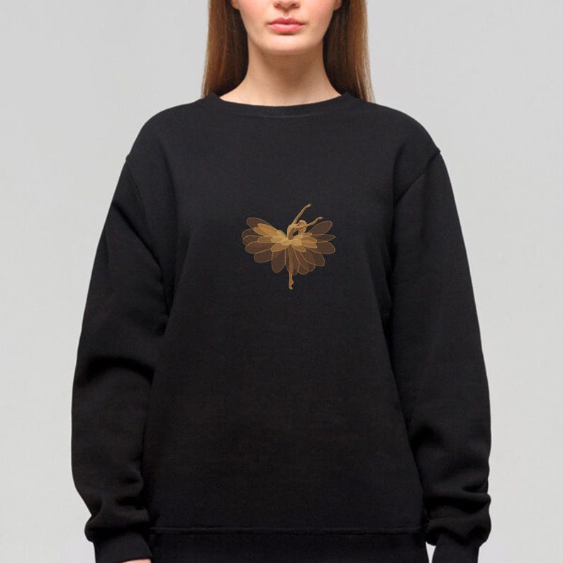 May include: Black sweatshirt featuring a gold-colored illustration of a ballerina in a flower-like design. The dancer is in a graceful pose, with arms and legs extended. The design is centered on the chest.