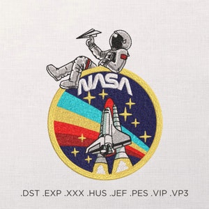 Könnte beinhalten: Gestickter Aufnäher mit einem Cartoon-Astronauten, der ein Papierflugzeug hält und auf einem NASA-Logo mit einem Raumschiff in der Mitte sitzt. Das Logo hat ein blaues, gelbes und rotes Farbschema mit weißen Sternen.