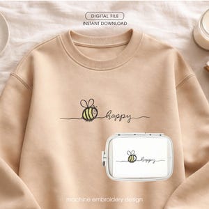 Op de afbeelding: Een beige sweatshirt met een bij en het woord "happy" geborduurd in zwart. Een witte borduurring met hetzelfde ontwerp staat op de voorgrond. De tekst "DIGITAL FILE INSTANT DOWNLOAD" en "machine embroidery design" zijn ook zichtbaar.
