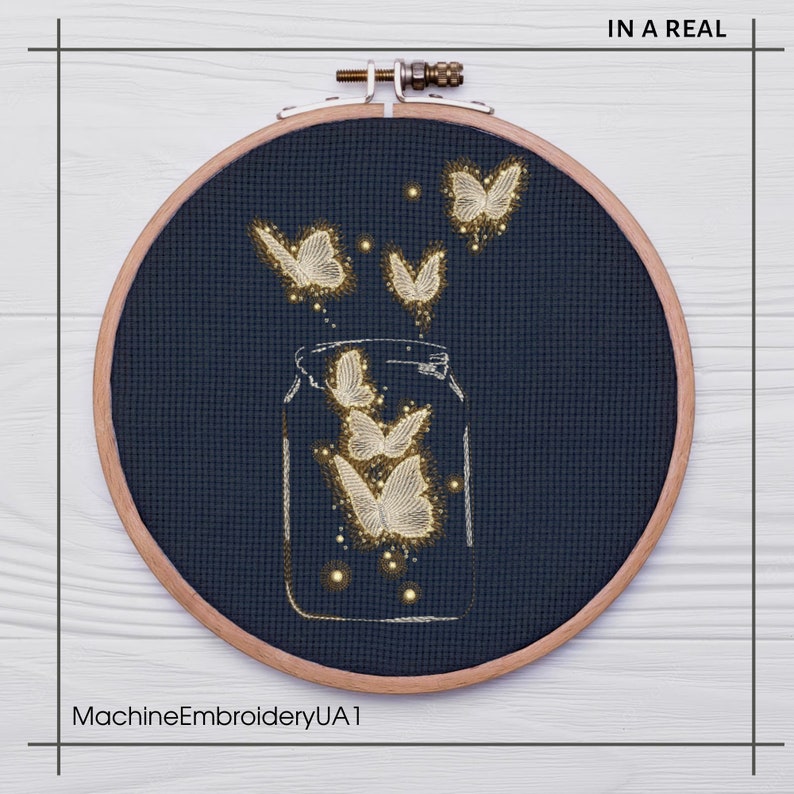 May include: A gold embroidery design of butterflies flying out of a glass jar on a dark blue fabric background. The design is in a wooden embroidery hoop. The text "IN A REAL" is in the top right corner of the image. The text "MachineEmbroideryUA1" is in the bottom left corner of the image.
