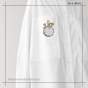 May include: White button-down shirt with a pocket featuring an embroidered image of The Little Prince sitting on an asteroid with a fox.