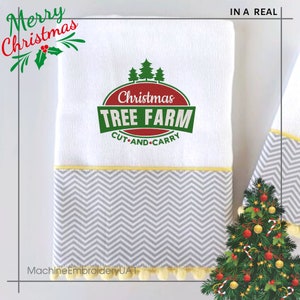 K&ouml;nnte beinhalten: Wei&szlig;es K&uuml;chentuch mit einem grauen und gelben Zickzackmuster am Rand. Das Tuch hat ein rotes, gr&uuml;nes und gelbes gesticktes Design mit der Aufschrift "Christmas Tree Farm Cut and Carry".