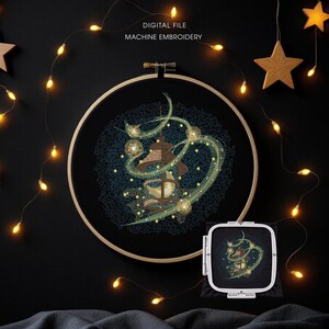 May include: An embroidery hoop with a detailed machine embroidery design featuring a stylized lantern with swirling green and gold accents. The text "DIGITAL FILE MACHINE EMBROIDERY" is visible. The scene is decorated with string lights and star-shaped ornaments.