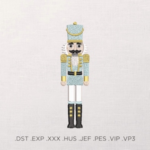 May include: An embroidered design of a traditional nutcracker soldier in light blue, gold, black, and white. The nutcracker wears a tall hat and a uniform with gold epaulets. The design is on a white background. Below the image are file type extensions.