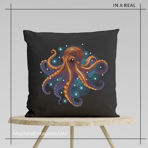 Puede incluir: Una almohada negra con una imagen bordada de un pulpo naranja con tent&aacute;culos morados rodeado de c&iacute;rculos azules y blancos. La almohada est&aacute; sentada en un taburete de madera.