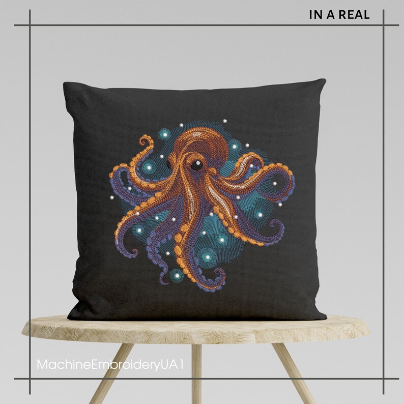 Puede incluir: Una almohada negra con una imagen bordada de un pulpo naranja con tent&aacute;culos morados rodeado de c&iacute;rculos azules y blancos. La almohada est&aacute; sentada en un taburete de madera.