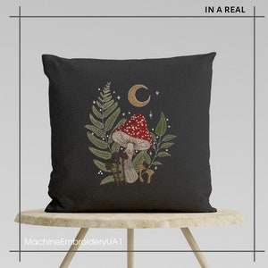 May include: A black pillow with a mushroom, fern, and crescent moon embroidered design. The embroidery is in shades of red, green, brown, and gold.