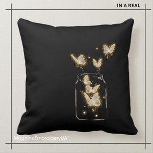 May include: Black throw pillow with a white embroidered design of a glass jar with butterflies flying out of it. The text "IN A REAL" is at the top of the pillow.