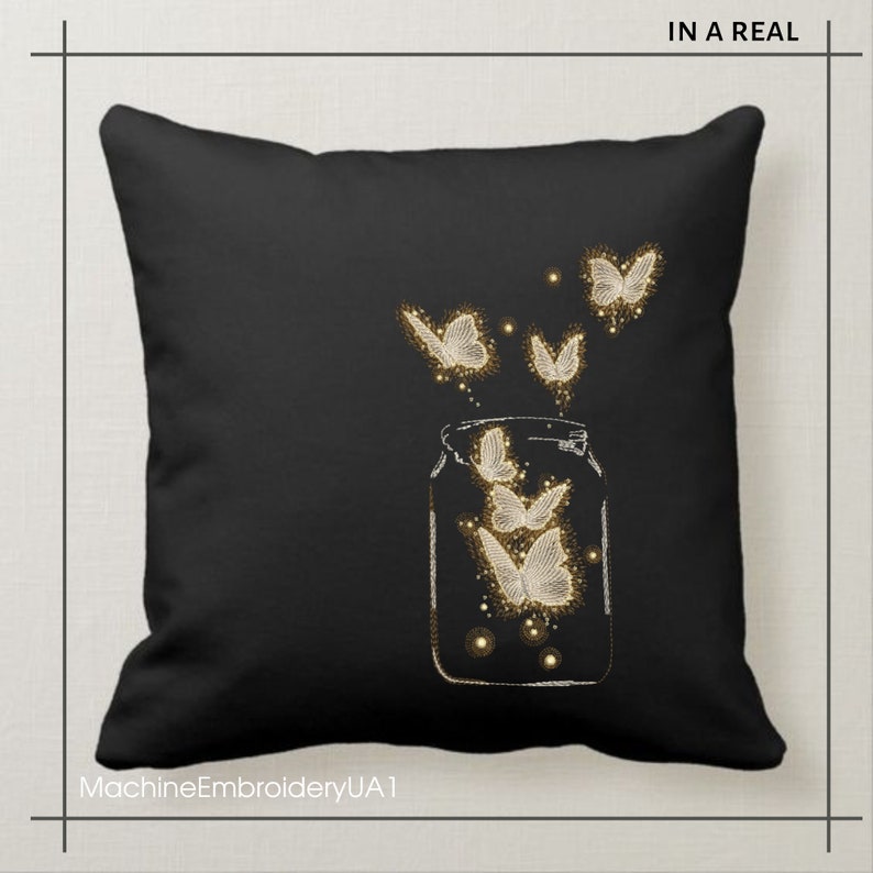 May include: Black throw pillow with a white embroidered design of a glass jar with butterflies flying out of it. The text "IN A REAL" is at the top of the pillow.