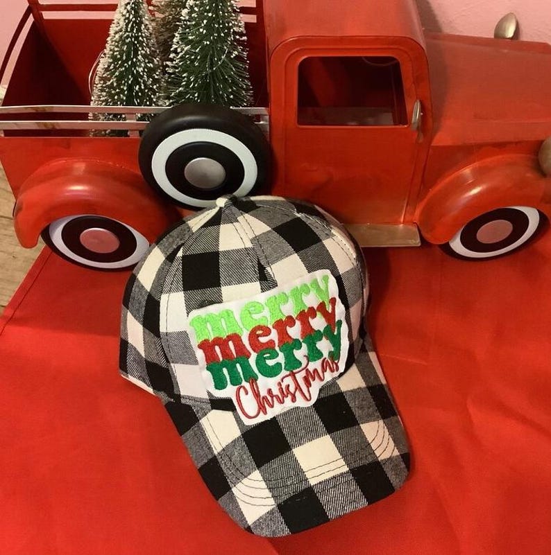 May include: A black and white buffalo plaid baseball cap featuring a white rectangular patch with the embroidered text merry merry merry Christmas in alternating green and red script and block lettering on the front panel.