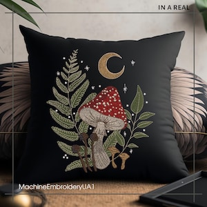 May include: Black pillow with embroidered design of a red and white mushroom, green leaves, and a crescent moon. The embroidery is done in white thread and the background is black.