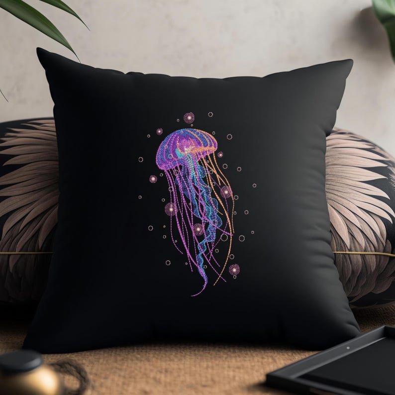 May include: A black pillow with a colorful embroidered jellyfish design. The jellyfish is surrounded by small white circles, resembling bubbles.