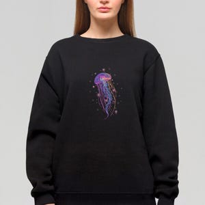 May include: A black sweatshirt with a colorful jellyfish graphic on the front. The jellyfish is surrounded by small, white circles that resemble bubbles.