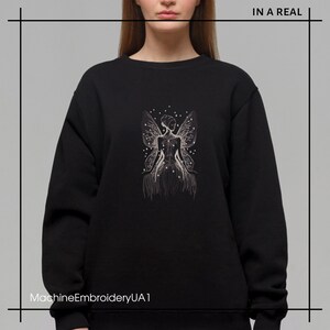 May include: Black sweatshirt with a white embroidered design of a fairy with wings and stars. The text "MachineEmbroideryUA1" is at the bottom of the image.
