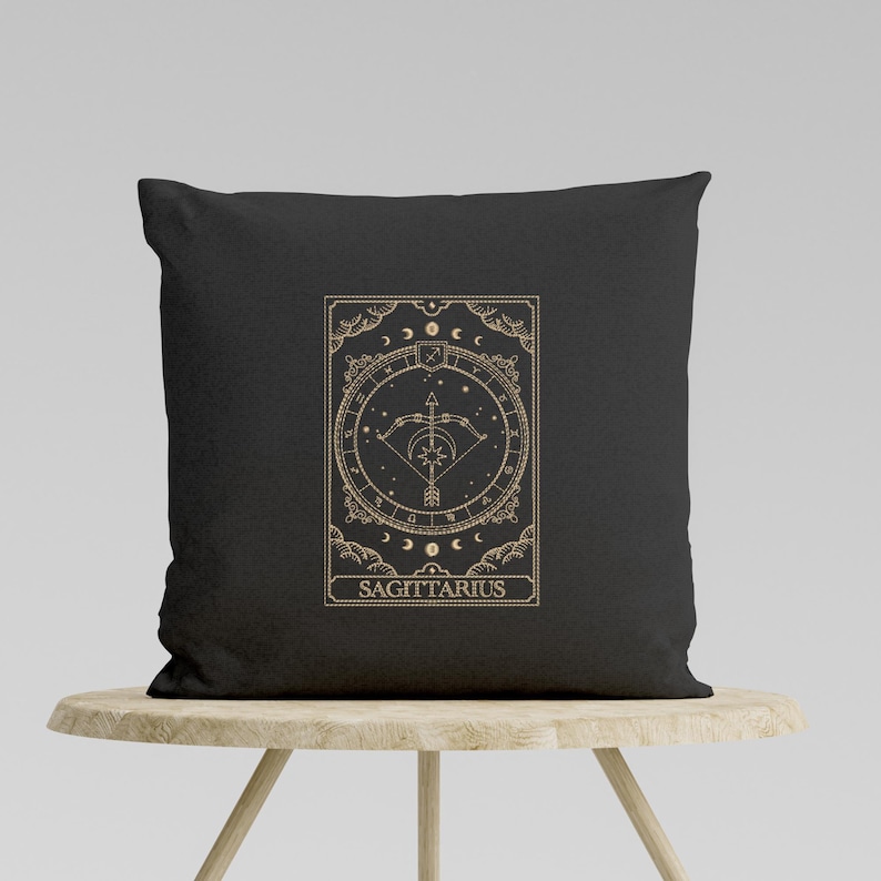 Pu&ograve; includere: Cuscino nero con un designo dorato del segno zodiacale Sagittario. Il design presenta una freccia e un arco all'interno di un cerchio con stelle e lune. Il testo "SAGITTARIO" &egrave; sotto il design.