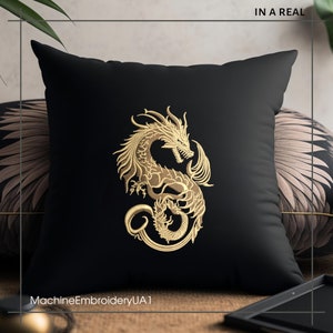 May include: Black throw pillow with gold embroidered dragon design. The pillow is on a brown surface with a gold tray and a plant in the background. The text "MachineEmbroideryUA1" is at the bottom of the pillow.