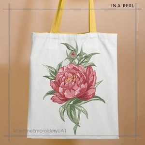 May include: A white tote bag with yellow handles features a pink peony flower with green leaves embroidered on the front. The text "MachineEmbroideryUA1" is printed on the bottom of the bag.
