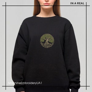 May include: Black sweatshirt with a green and brown embroidered tree of life design. The text "IN A REAL" is in the top right corner of the image. The text "MachineEmbroideryUA1" is in the bottom left corner of the image.