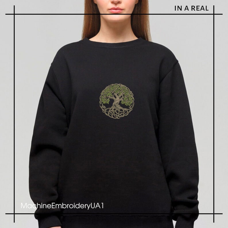 May include: Black sweatshirt with a green and brown embroidered tree of life design. The text "IN A REAL" is in the top right corner of the image. The text "MachineEmbroideryUA1" is in the bottom left corner of the image.
