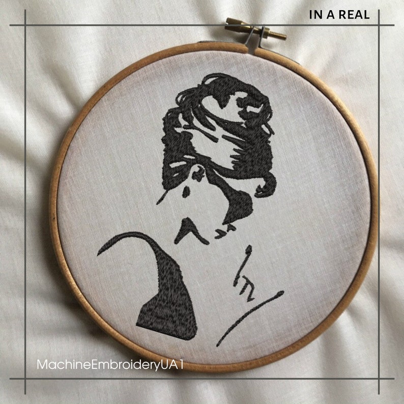 May include: Black and white embroidered image of a woman's face in a circular wooden embroidery hoop. The text "IN A REAL" is at the top of the hoop and the text "MachineEmbroideryUA1" is at the bottom.