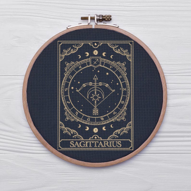 Pu&ograve; includere: Un cerchio da ricamo dorato e nero con un designo del segno zodiacale Sagittario. Il design presenta un arco e una freccia, stelle e la parola "Sagittario".