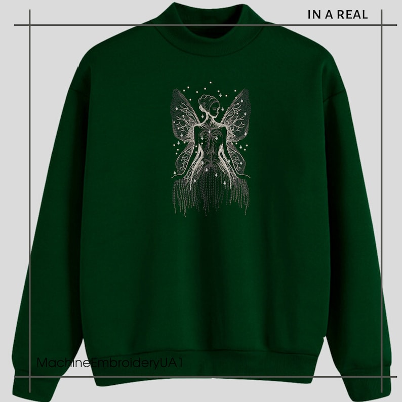 May include: A dark green sweatshirt with a white embroidered design of a fairy with wings and stars. The text "IN A REAL" is in the top right corner of the image.