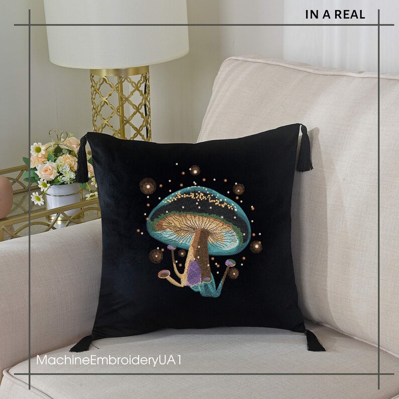 May include: A black velvet throw pillow with a blue and green mushroom embroidered on it. The mushroom has a gold stem and is surrounded by small gold dots. The pillow has tassels on each corner. "MachineEmbroideryUA1" is printed on the bottom of the pillow.