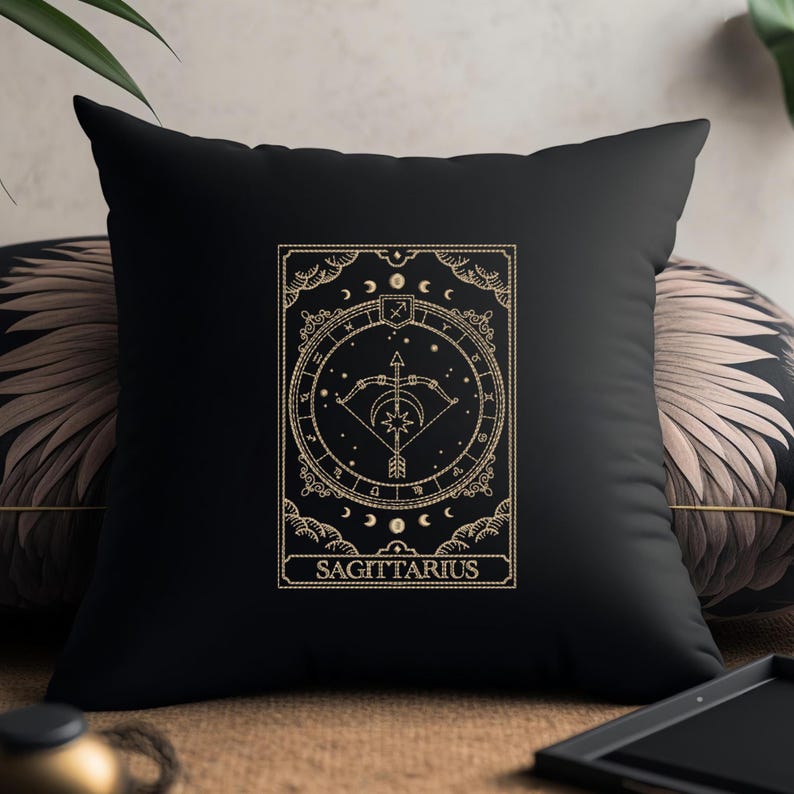 Pu&ograve; includere: Cuscino nero con un disegno ricamato in oro di un simbolo zodiacale, un arco e una freccia, e la parola "SAGITTARIO".