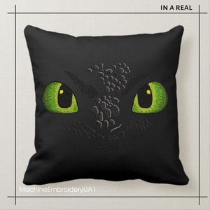 Pu&ograve; includere: Cuscino nero con un viso di drago verde ricamato. Il drago ha grandi occhi verdi con pupille gialle. Il testo "MachineEmbroideryUA1" &egrave; nella parte inferiore del cuscino.