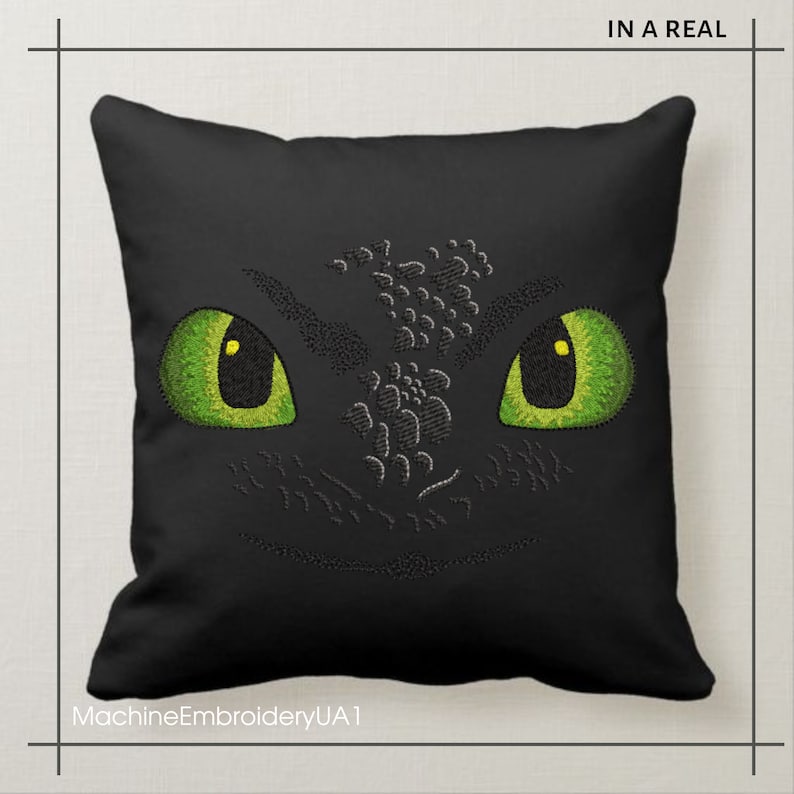 Pu&ograve; includere: Cuscino nero con un viso di drago verde ricamato. Il drago ha grandi occhi verdi con pupille gialle. Il testo "MachineEmbroideryUA1" &egrave; nella parte inferiore del cuscino.