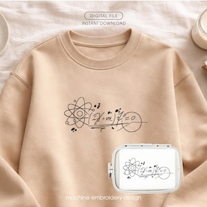 Può includere: Una felpa beige con una grafica nera di un atomo e un'equazione matematica. Il testo "DIGITAL FILE INSTANT DOWNLOAD" è in alto e "machine embroidery design" in basso. È visibile anche un telaio da ricamo con lo stesso disegno.