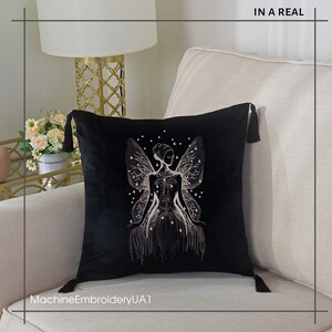May include: Black velvet throw pillow with a white embroidered design of a fairy with wings. The pillow has tassels on each corner.