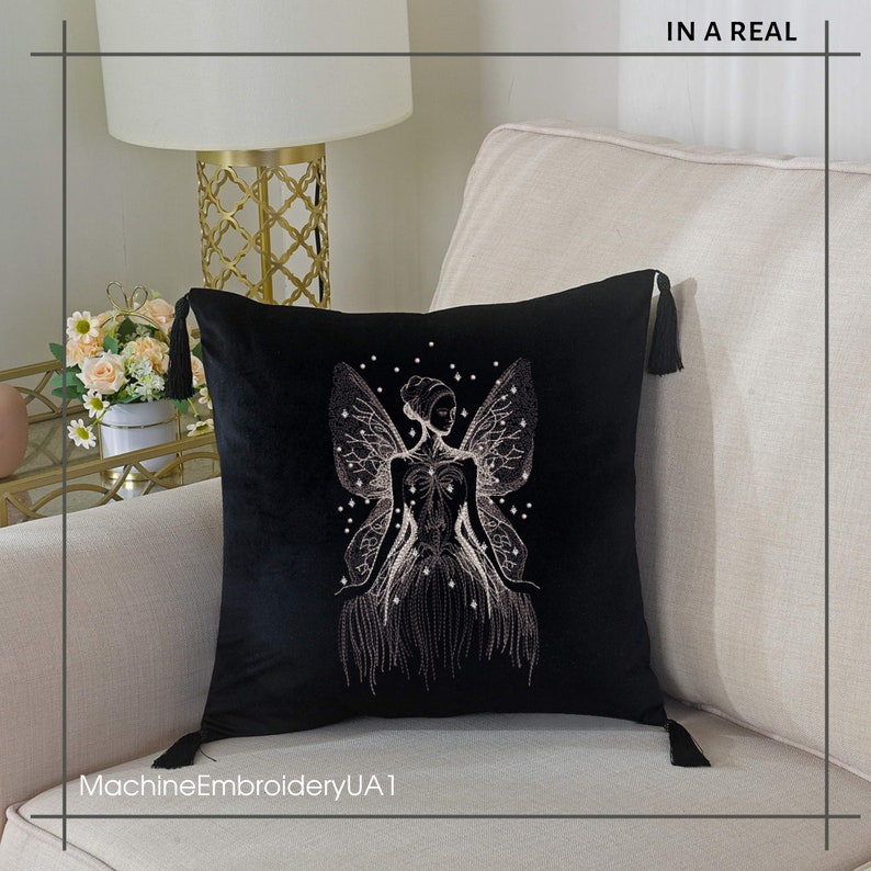 May include: Black velvet throw pillow with a white embroidered design of a fairy with wings. The pillow has tassels on each corner.