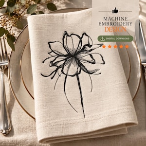 Op de afbeelding: Een beige linnen servet met een zwart, machinaal geborduurd lijntekeningontwerp van een bloem. De tekst luidt MACHINE EMBROIDERY DESIGN en DIGITAL DOWNLOAD. Het servet ligt op een bord met een vork en mes zichtbaar aan de zijkanten.